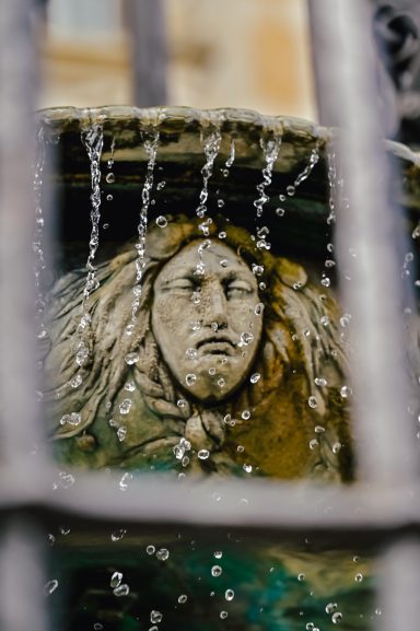 Brunnenschnitzerei trauriges Gesicht